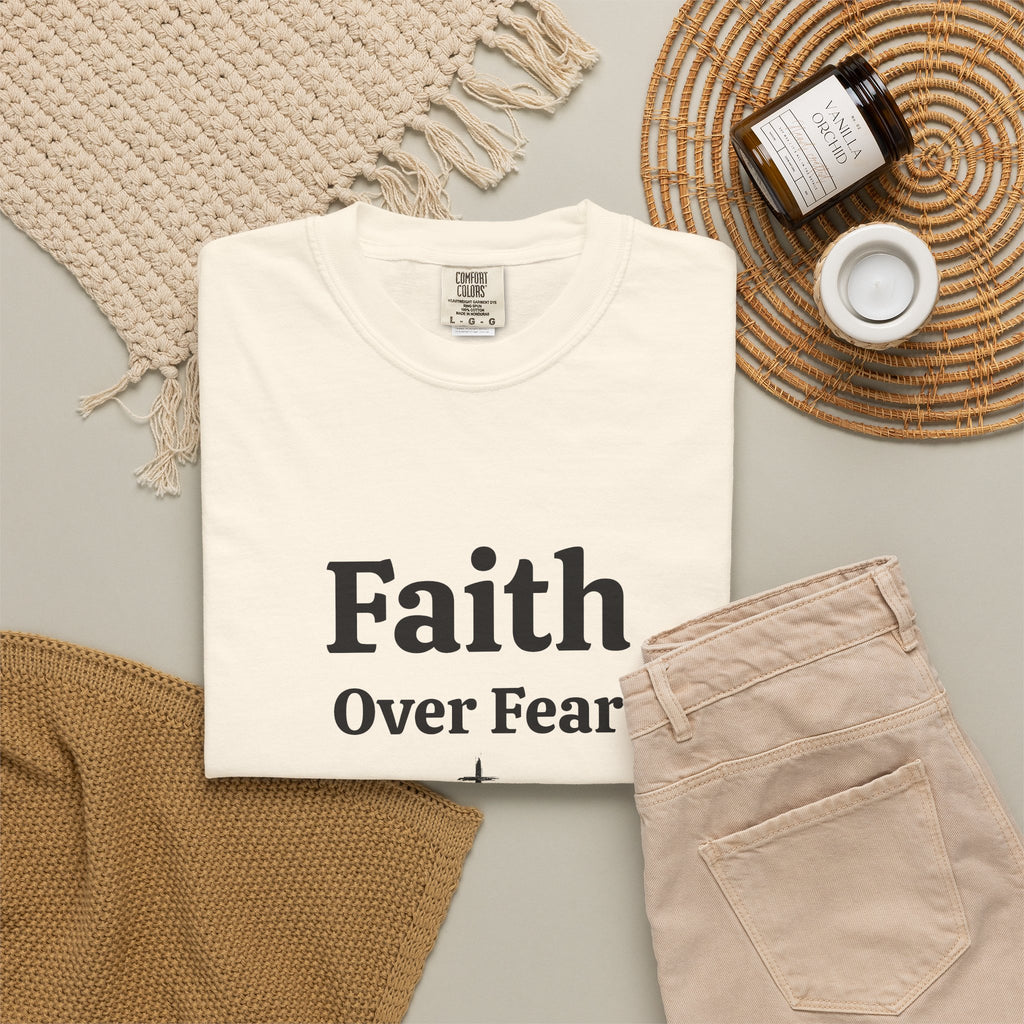 Ivory Faith Over Fear tee folded in a flat lay with jeans and candle