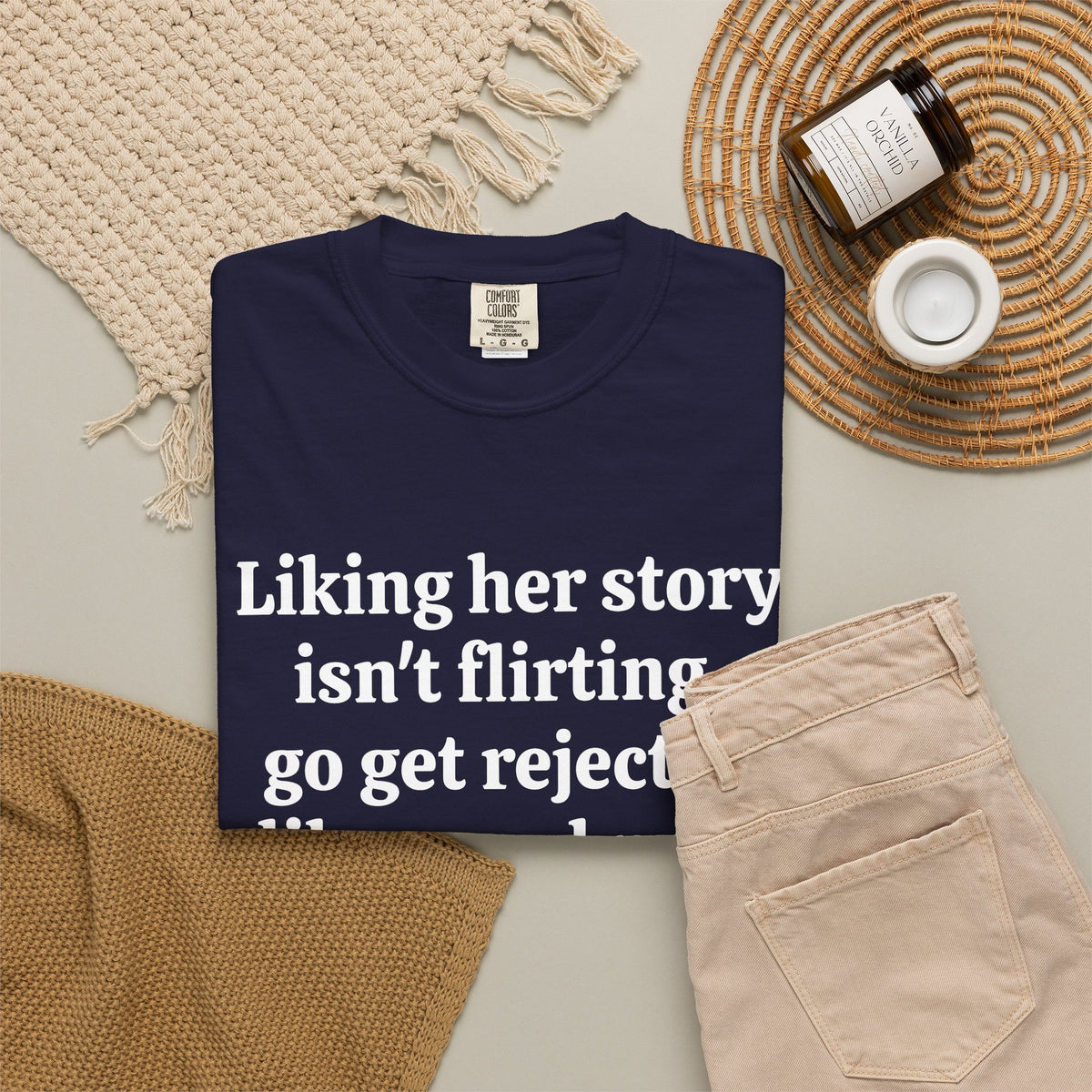 True Navy Rejected Like A Real Man tee folded in a flat lay with jeans and candle