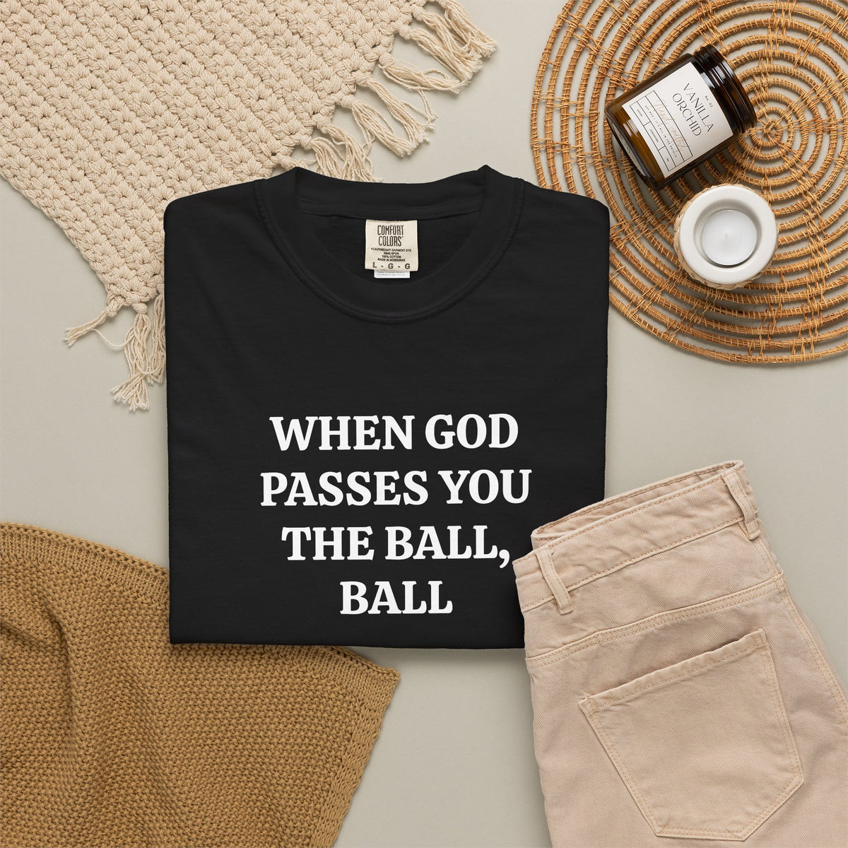 Black When God Passes You The Ball, Ball tee folded in a flat lay with jeans and candle
