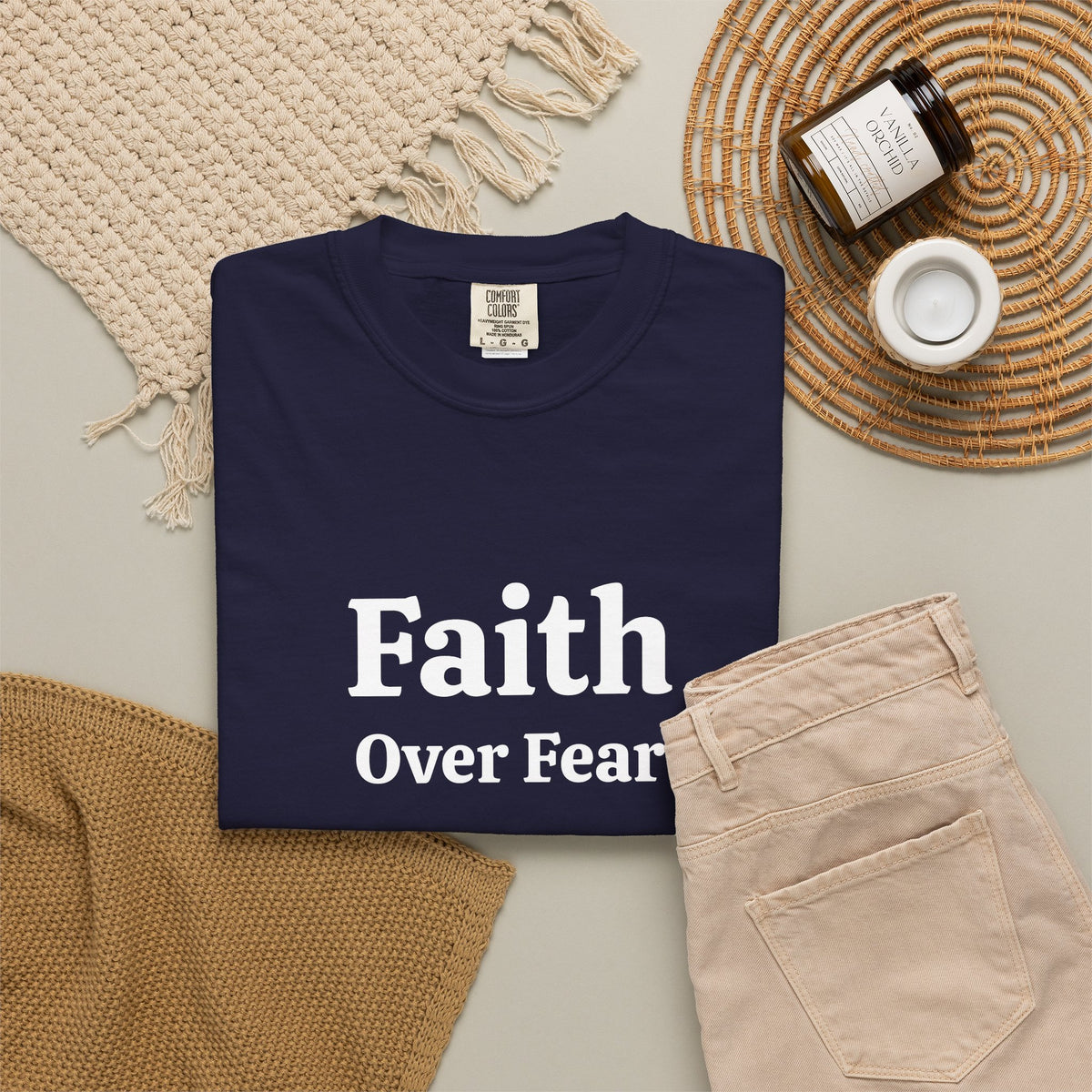 True Navy Faith Over Fear tee folded in a flat lay with jeans and candle