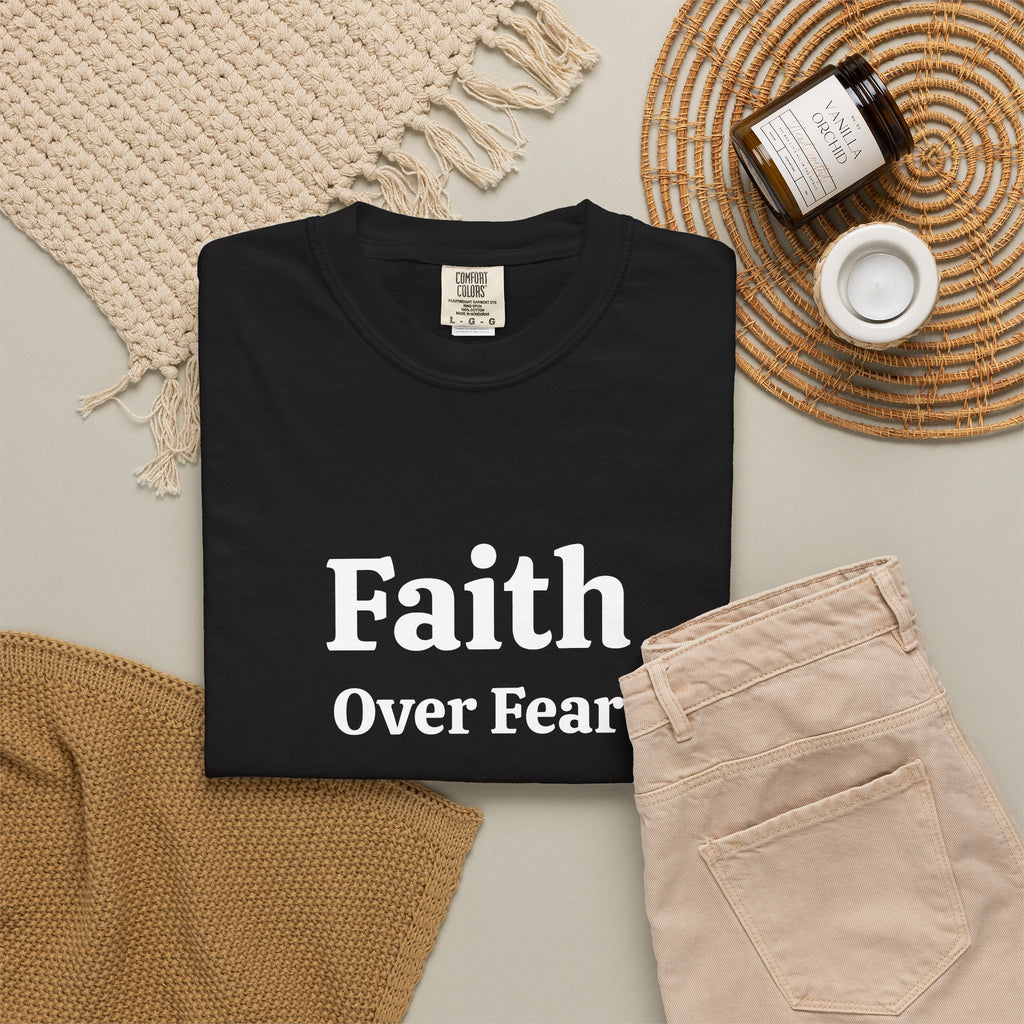 Black Faith Over Fear tee folded in a flat lay with jeans and candle