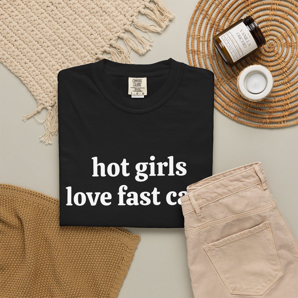 Black Hot Girls Love Fast Cars tee folded in a flat lay with jeans and candle