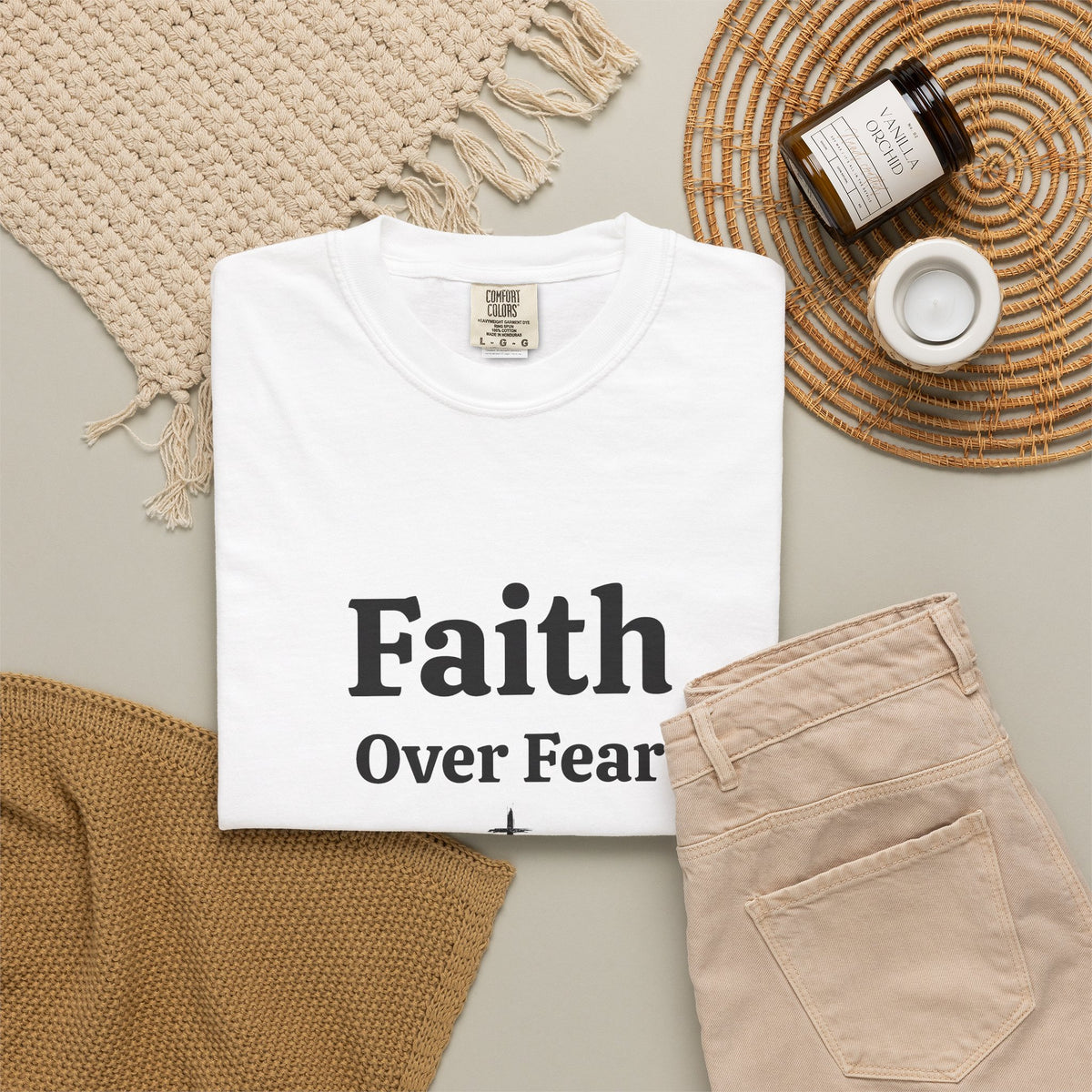 White Faith Over Fear tee folded in a flat lay with jeans and candle